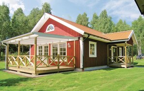 Et rødt træhus med en overdækket veranda og egen indgang.