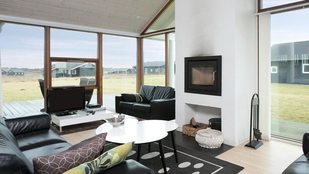 Ein modernes Wohnzimmer mit großem Fenster, Kamin und Fernseher.