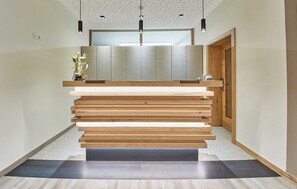 Un espace d’accueil moderne avec un escalier en bois, un comptoir d’accueil et une grande fenêtre.