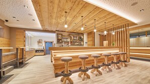 Eine moderne Bar mit Holzeinrichtung, Barhocker und einer gut beleuchteten Decke.