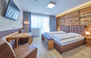 Une chambre d’hôtel équipée d’un lit, d’un bureau, d’une chaise, d’une télévision et d’un panneau mural en bois.