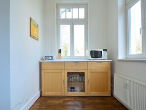 Une cuisine avec des meubles de rangement en bois, un four à micro-ondes et une fenêtre au-dessus de l’évier.