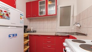 A compact kitchen with red cabinets, a white refrigerator, a stove, and a sink. - Amazing apartment in Jadrija with WiFi (Jadrija)