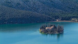 An isolated island with a building surrounded by trees, located in a large body of water with a mountainous backdrop. - Amazing apartment in Jadrija with WiFi (Jadrija)