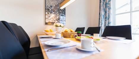 Een eetgedeelte met een tafel voor vier personen, inclusief borden, bekers en een broodmand.