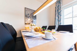 Ein Essbereich mit einem Tisch, der für vier Personen gedeckt ist, inklusive Tellern, Tassen und einem Brotkorb.