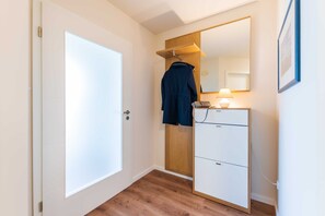 A hallway with a wooden wardrobe, a mirror, and a white door.