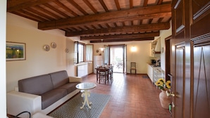 Un salón acogedor con un sofá, una mesita redonda y un tapete estampado. Cuenta con una zona de cocina con estufa, fregadero y armarios.