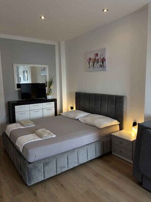 A modern bedroom with a bed, bedside tables, a television, and a painting on the wall. - Studio with air conditioning and terrace (Dramalj)