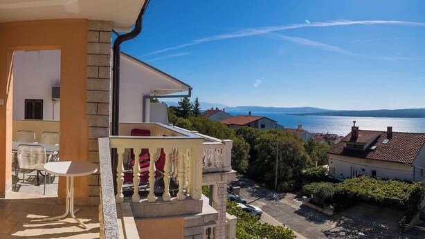 Ein Balkon mit Tisch und Stühlen mit Blick auf ein Gewässer und eine Stadt.