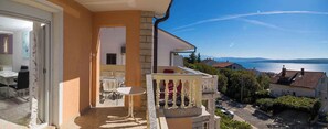 A balcony with a table and chairs, overlooking a body of water and a town. - Studio with air conditioning and terrace (Dramalj)