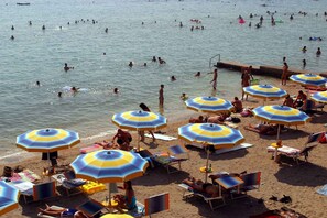 A beach with multiple umbrellas and sun loungers.