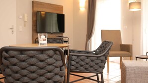 Un comedor moderno con una mesa de madera, dos sillas tapizadas, un televisor montado en la pared y una lámpara.