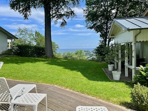 Eine Terrasse mit Stühlen, ein kleiner Garten und Meerblick.