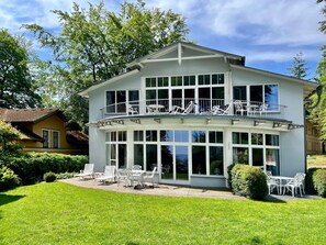 En tvåvåningsbyggnad med en balkong, stora fönster och utomhusplatser.