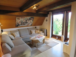 A cozy living room with a large sofa, a small table, and a painting on the wall.