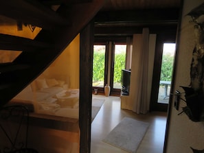 Ein Schlafzimmer mit Bett, Fernseher und Blick auf einen Balkon.