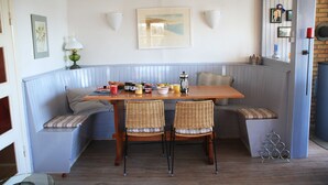 A corner seating area with a wooden table, two wicker chairs, and a bench with cushions. - RED Holiday home at the Bistensee - Holiday home Frick (Alt Duvenstedt)