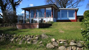 A modern house with large windows, a brick foundation, and a stone wall in the foreground. - RED Holiday home at the Bistensee - Holiday home Frick (Alt Duvenstedt)