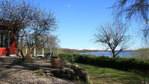 A lakeside garden with a gravel path, potted plants, and a view of a lake and mountains. - RED Holiday home at the Bistensee - Holiday home Frick (Alt Duvenstedt)