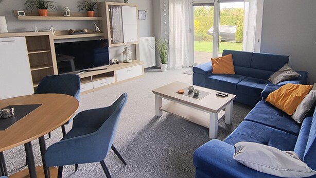 A living room with a sofa, a coffee table, a TV, and a dining area with chairs. - Reriker Straße 06b Whg. RER6b-2 .. - Reriker Str. 6b Whg. RER6b-02 (Kühlungsborn)