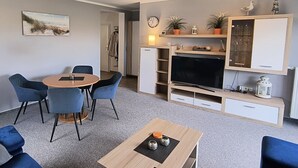 A modern living room with a dining area, a flat-screen TV, and a coat rack. - Reriker Straße 06b Whg. RER6b-2 .. - Reriker Str. 6b Whg. RER6b-02 (Kühlungsborn)