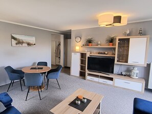 A modern living room with a dining area, a flat-screen TV, and a coat rack. - Reriker Straße 06b Whg. RER6b-2 .. - Reriker Str. 6b Whg. RER6b-02 (Kühlungsborn)