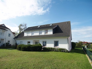 A two-story house with a tiled roof, a small balcony, and a well-maintained lawn. - Reriker Straße 06b Whg. RER6b-2 .. - Reriker Str. 6b Whg. RER6b-02 (Kühlungsborn)