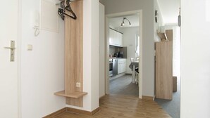 A hallway with a wooden door, a coat rack, and a kitchen visible through an open door. - Reriker Straße 06b Whg. RER6b-2 .. - Reriker Str. 6b Whg. RER6b-02 (Kühlungsborn)