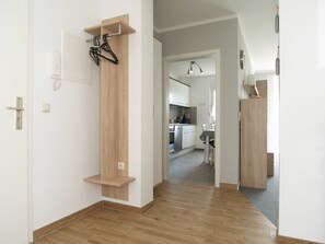 A hallway with a wooden door, a coat rack, and a kitchen visible through an open door. - Reriker Straße 06b Whg. RER6b-2 .. - Reriker Str. 6b Whg. RER6b-02 (Kühlungsborn)