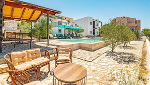 A poolside area with wicker furniture, a stone table, and a stone pool.