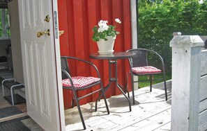 An outdoor seating area with two chairs and a table, a red door, and a white potted plant. - 1 bedroom amazing home in Visby (Visby)