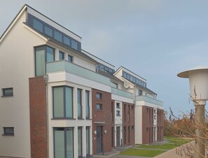 A modern multi-story residential building with large windows, a flat roof, and a brick facade.