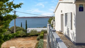 Un edificio blanco con un cartel que indica que es un apartamento, un camino de piedra y vistas a un lago.