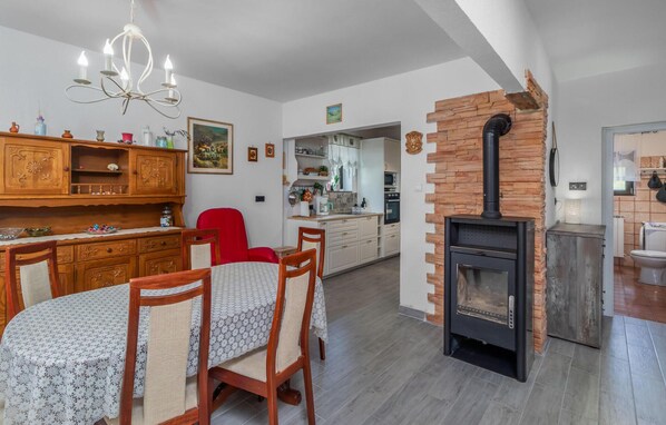 Une cuisine moderne dotée d’un îlot central, d’un coin repas avec une table et des chaises, et d’un poêle à bois encastré.