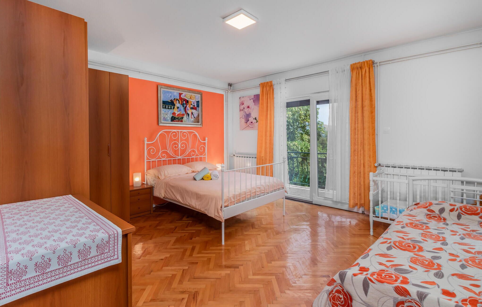 Un dormitorio con cama, mesita de noche, ventana con cortinas y radiador.