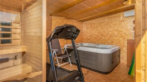 Een houten interieur met een loopband, een stoel en een whirlpool.