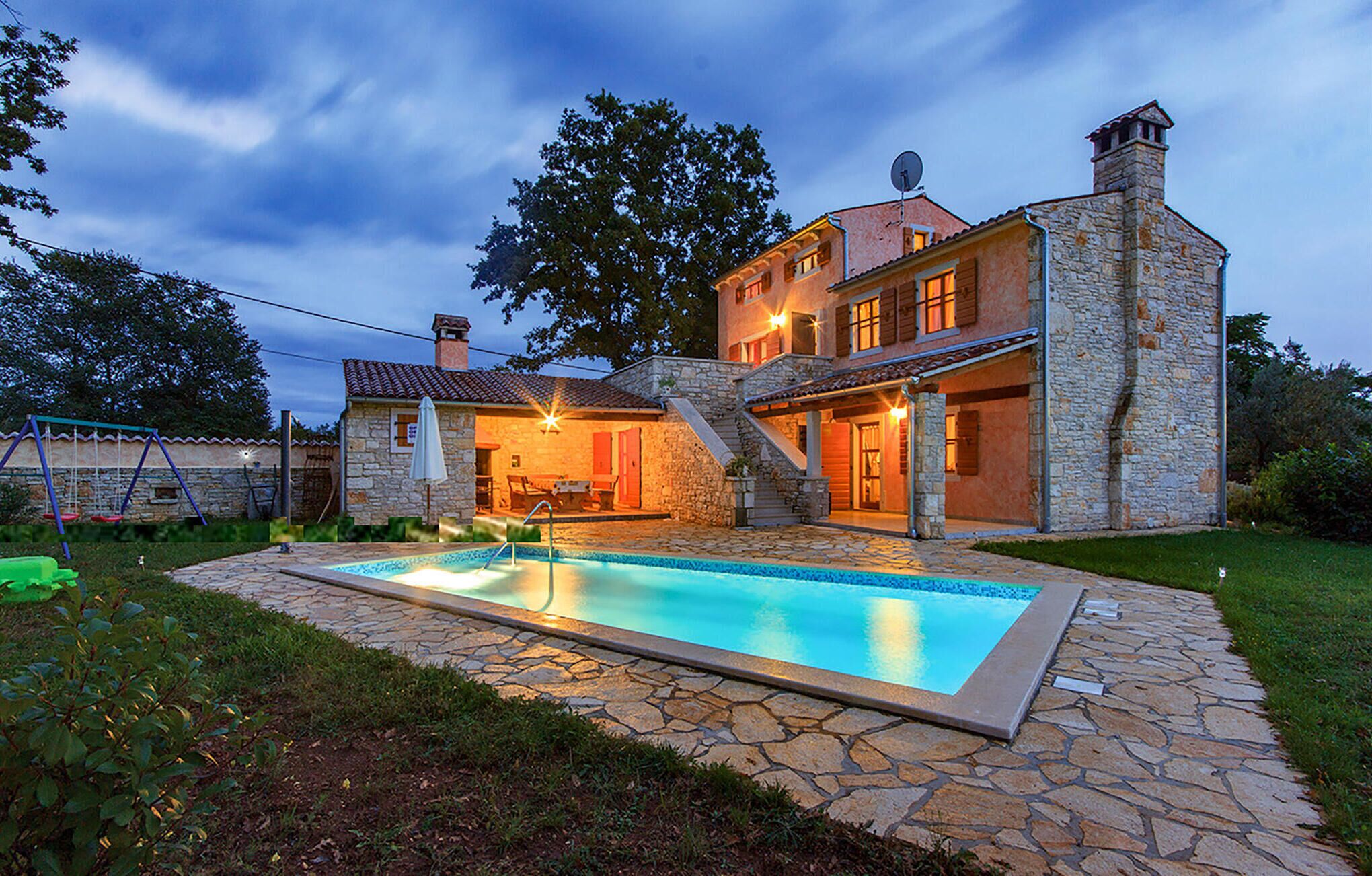 Une maison en pierre avec une piscine, un espace salon extérieur et un escalier en pierre.