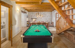 A pool table in a room with a stone wall, wooden ceiling beams, and a staircase. - Amazing home in Boduleri (Boduleri)