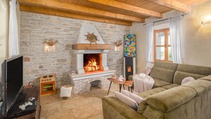 A cozy living room with a stone fireplace, a television, and a comfortable sofa. - Amazing home in Boduleri (Boduleri)