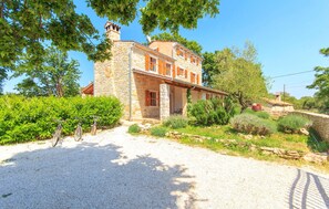 A stone house with a gravel driveway, surrounded by greenery and trees. - Amazing home in Boduleri (Boduleri)