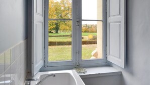 A bathroom with a window, a sink, and a mirror.