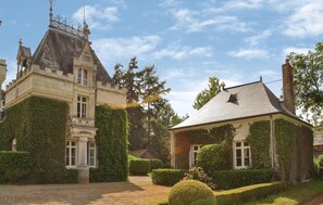 Un bâtiment historique doté d’une tour et de murs couverts de lierre, entouré de haies et d’arbres bien entretenus.