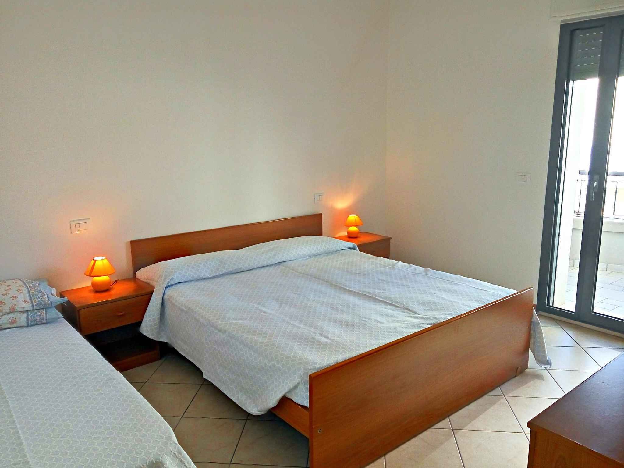 A bedroom with two beds, a wooden headboard, bedside lamps, and a view through a glass door.