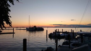 Ein Yachthafen im Abendlicht mit anlegenden Booten, ruhigem Wasser und wolkenlosem Himmel.