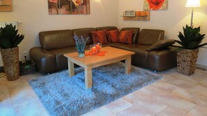 A living room with a brown leather sofa, a wooden coffee table, and two potted plants. - Herring Gull - Herring Gull (Heringsdorf)