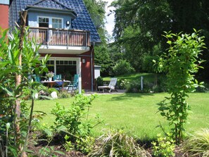 A house with a balcony, a lawn, and some plants.