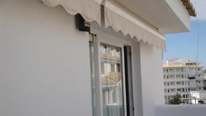 Een wit gebouw met een balkon en een raam met gordijn.