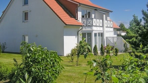 A two-story house with a red roof, white exterior walls, and a balcony with a railing. - Reriker Straße RER20-02. - Reriker Straße 20 Whg. 02 (Kühlungsborn)