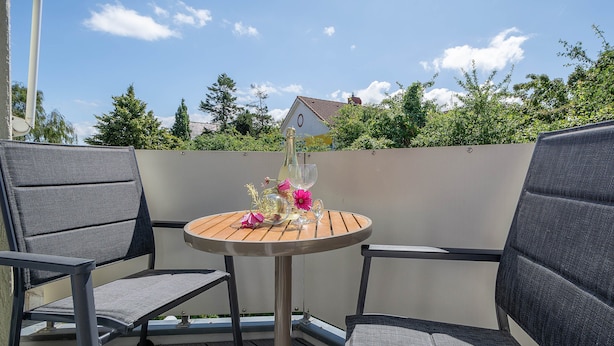 A round table with two chairs on a balcony, a bottle of champagne, and a glass on the table. - Reriker Straße RER20-02. - Reriker Straße 20 Whg. 02 (Kühlungsborn)